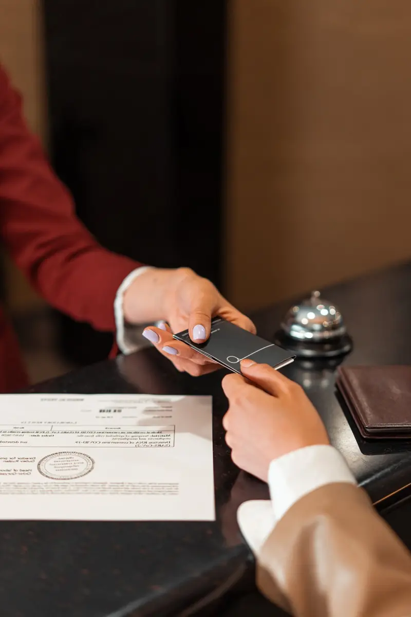 Hotel key card handed over at a reception desk, hands only